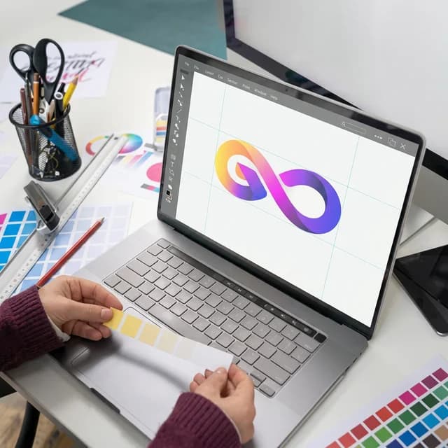 Designer working on a colorful logo with color swatches on desk